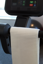 Load image into Gallery viewer, Towel hanging on handle of exercise machine in the gym.